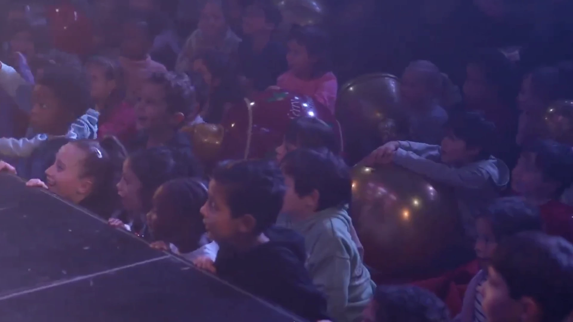 Children in the audience of a family magic show with balloons